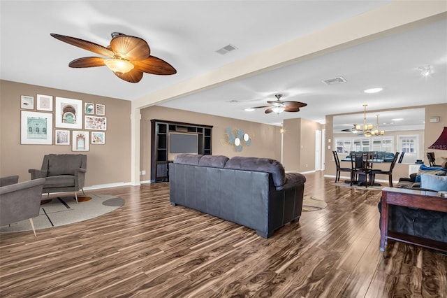 living room with ceiling fan with notable chandelier, dark wood-type flooring, and beamed ceiling