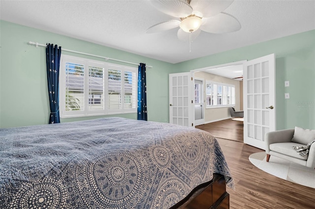 bedroom featuring dark hardwood / wood-style floors, ceiling fan, a textured ceiling, and french doors