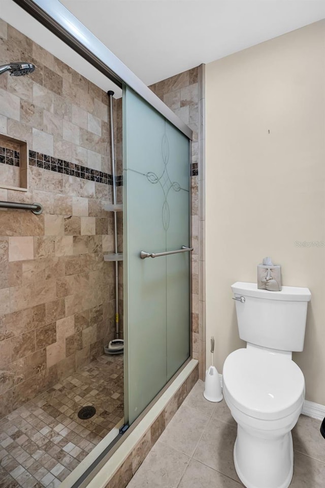 bathroom featuring a shower with shower door, tile patterned floors, and toilet