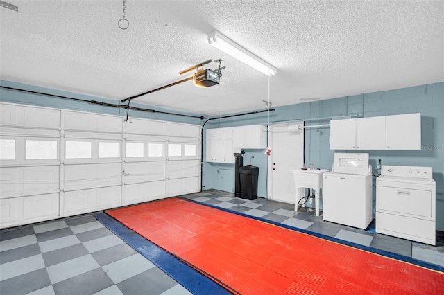 garage featuring a garage door opener, sink, and washer and dryer