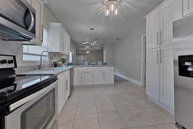 kitchen with sink, stainless steel appliances, white cabinets, kitchen peninsula, and light tile patterned flooring