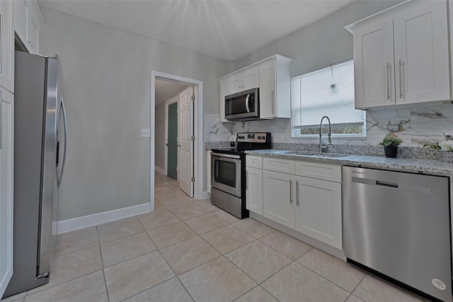 kitchen featuring sink, stainless steel appliances, light stone counters, decorative backsplash, and white cabinets