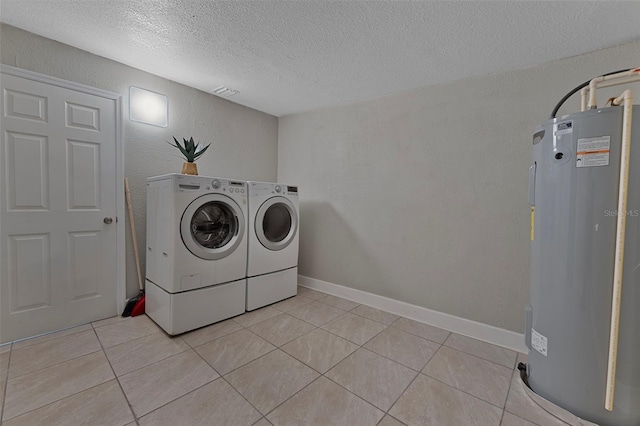 laundry room with water heater, washer and clothes dryer, light tile patterned floors, and a textured ceiling