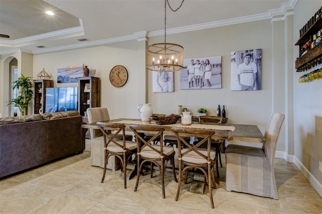 dining space with a raised ceiling, ornamental molding, light tile patterned floors, and a chandelier