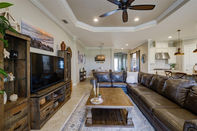 tiled living room with a tray ceiling, crown molding, and ceiling fan