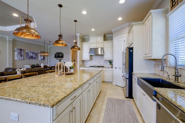 kitchen featuring sink, decorative light fixtures, appliances with stainless steel finishes, a large island, and light stone counters