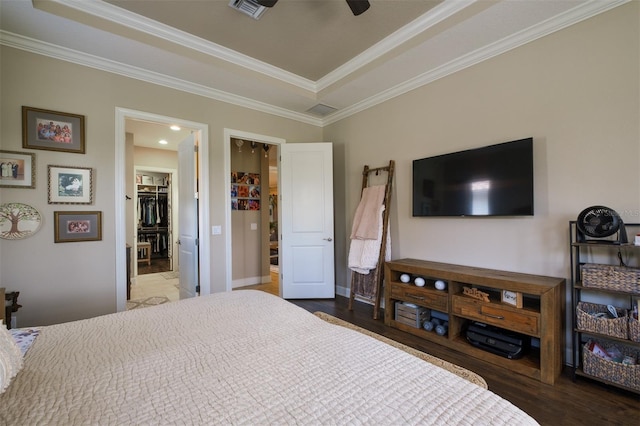 bedroom featuring a walk in closet, crown molding, ceiling fan, dark hardwood / wood-style floors, and a closet