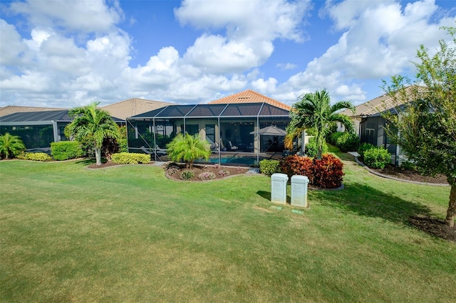 rear view of property featuring a lanai and a yard