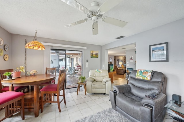 tiled living room featuring ceiling fan and a textured ceiling