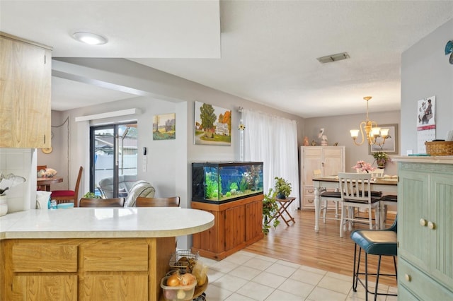 kitchen with kitchen peninsula, light tile patterned floors, hanging light fixtures, and a notable chandelier