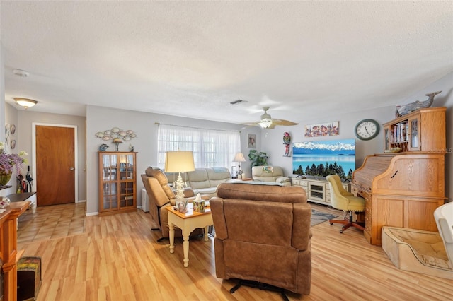 living room with ceiling fan, light hardwood / wood-style floors, and a textured ceiling