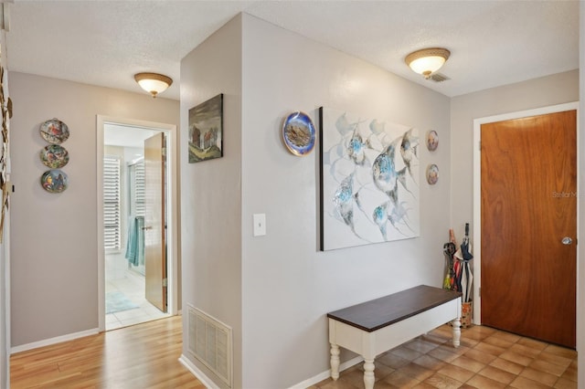 entryway with a textured ceiling and light wood-type flooring