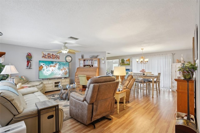 living room with a textured ceiling, light hardwood / wood-style flooring, and ceiling fan with notable chandelier