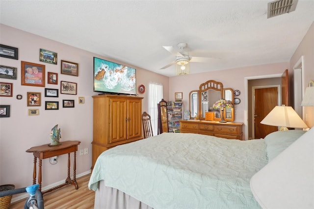 bedroom featuring ceiling fan, light hardwood / wood-style floors, and a textured ceiling