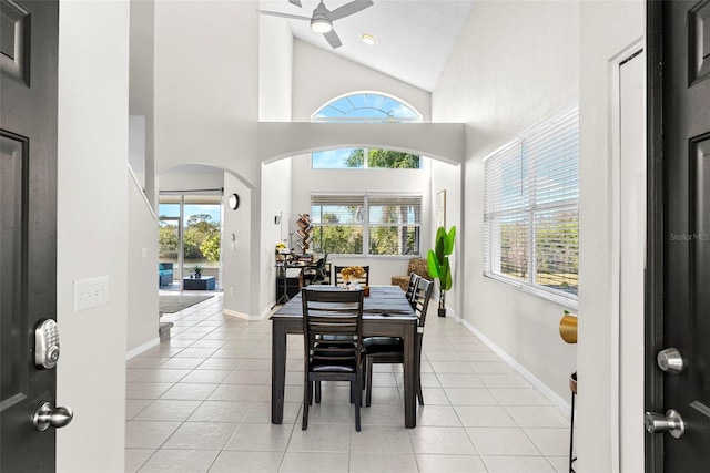 tiled dining room with ceiling fan and high vaulted ceiling