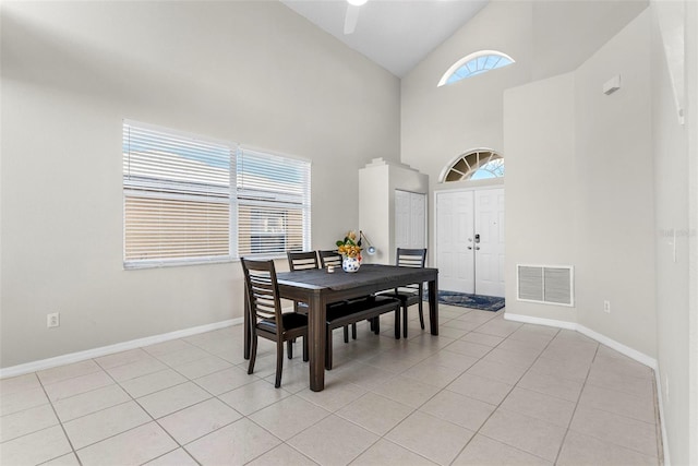 tiled dining area with high vaulted ceiling, plenty of natural light, and ceiling fan