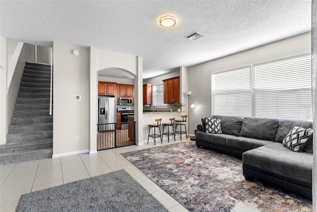 living room with a textured ceiling, light tile patterned flooring, and sink