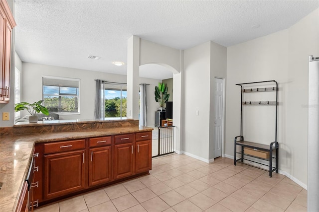 kitchen with stone counters, light tile patterned flooring, and a textured ceiling