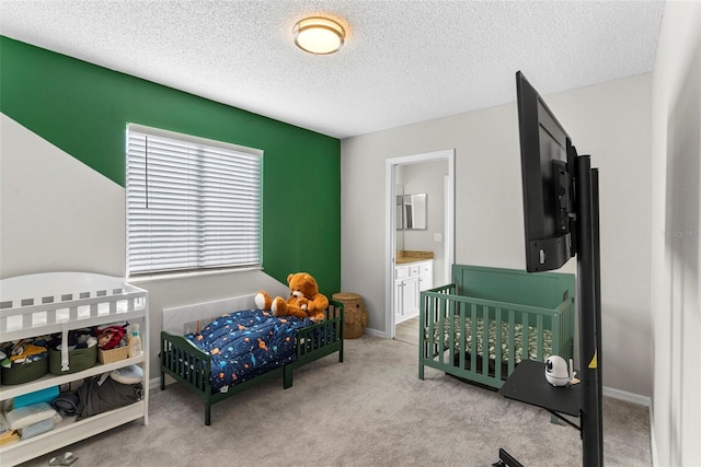 carpeted bedroom featuring a textured ceiling and ensuite bathroom