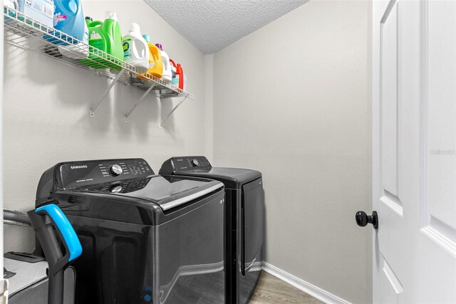 laundry area with washer and clothes dryer, dark hardwood / wood-style floors, and a textured ceiling