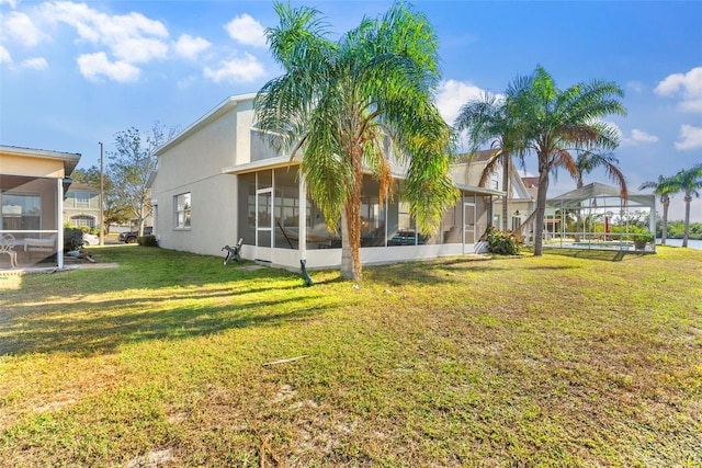 rear view of house with a sunroom and a yard