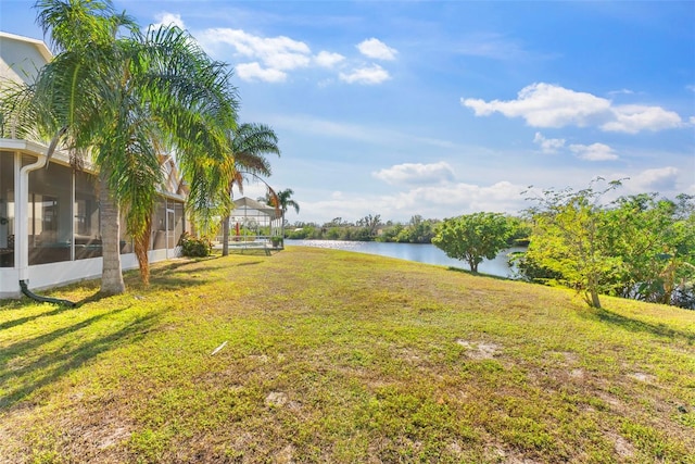 view of yard with a sunroom and a water view