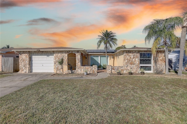 single story home featuring solar panels, a garage, and a lawn