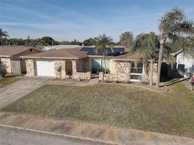 ranch-style house with solar panels, a garage, and a front lawn