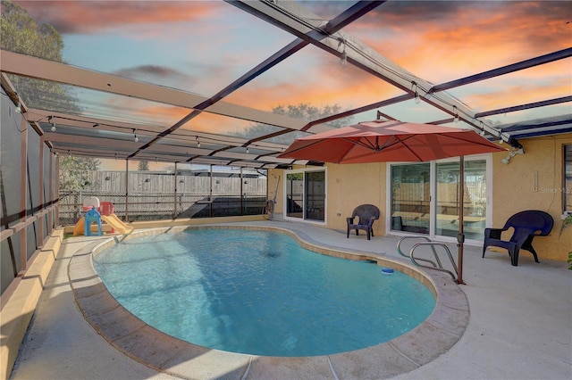 pool at dusk with a lanai and a patio area