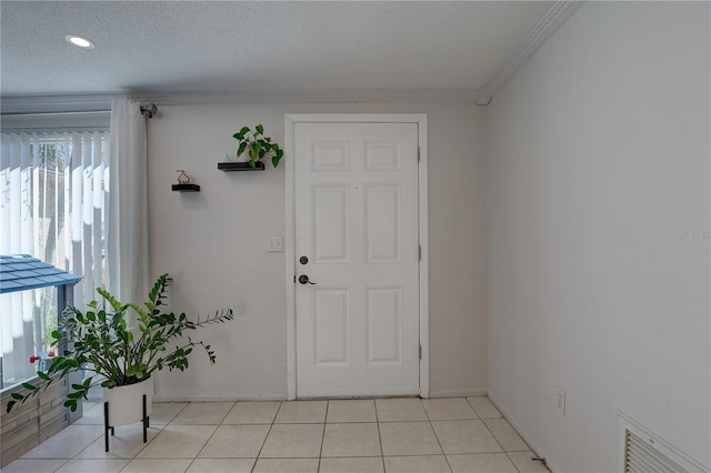 foyer with crown molding, light tile patterned floors, and a textured ceiling