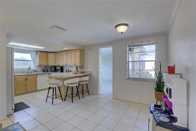 kitchen with light brown cabinets, crown molding, a textured ceiling, white appliances, and a breakfast bar area