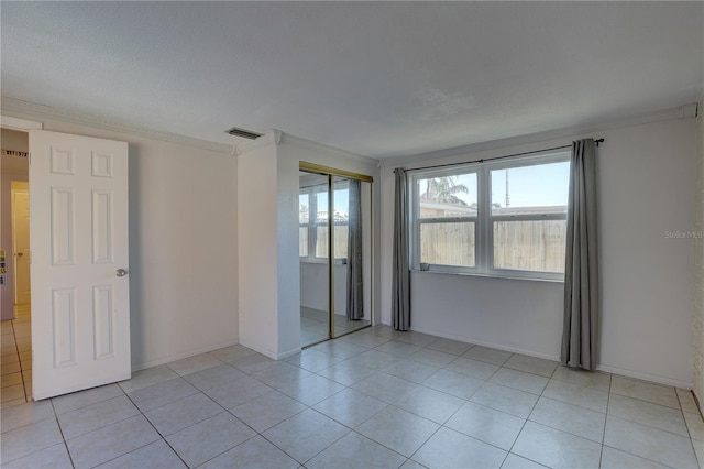 tiled empty room featuring crown molding