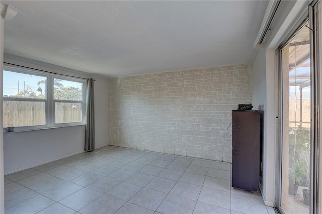 unfurnished room featuring light tile patterned floors and brick wall