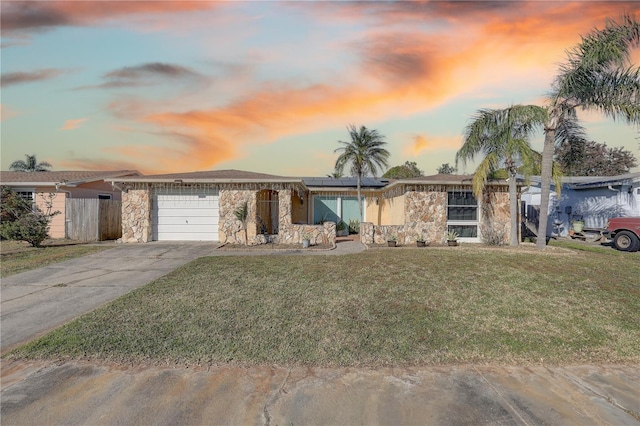 single story home featuring solar panels, a garage, and a lawn