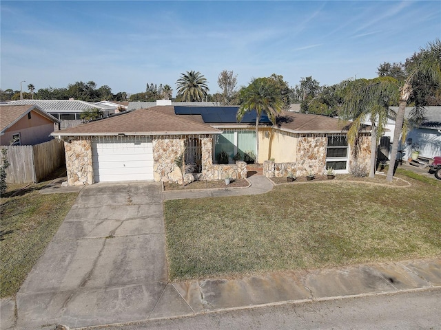 ranch-style home with a garage, a front yard, and solar panels