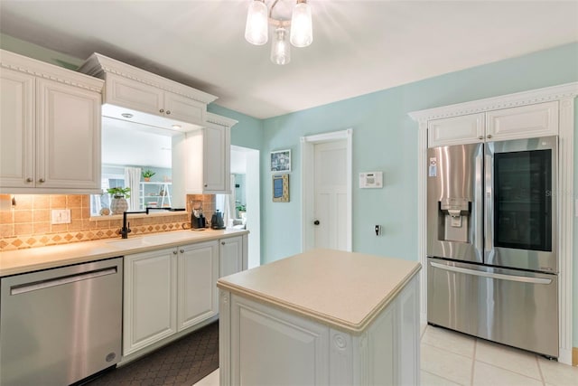 kitchen with a center island, tasteful backsplash, white cabinets, appliances with stainless steel finishes, and sink