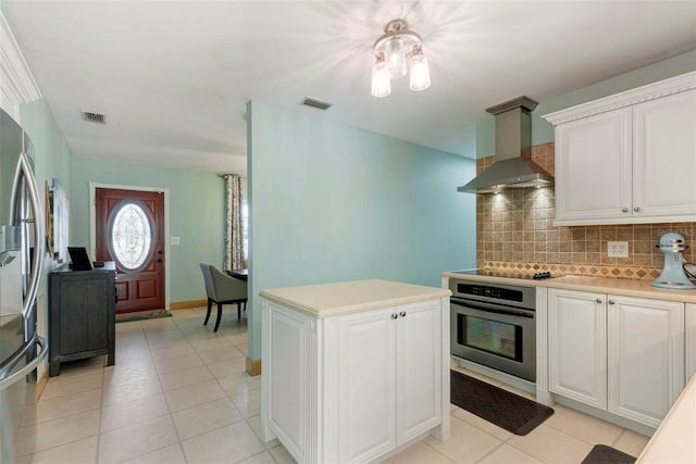 kitchen featuring white cabinets, light tile patterned floors, decorative backsplash, exhaust hood, and appliances with stainless steel finishes