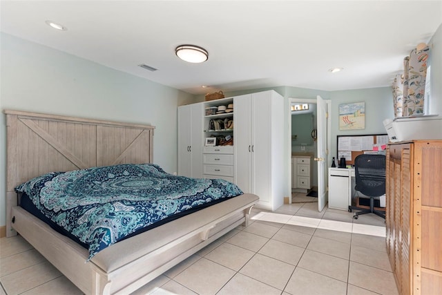 bedroom featuring ensuite bathroom and light tile patterned floors