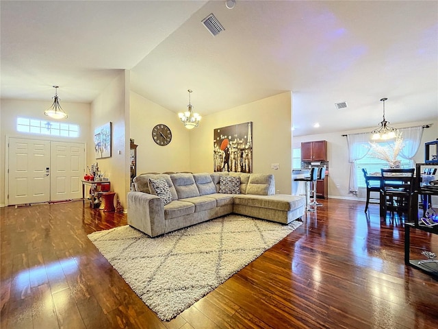 living room with a chandelier, a high ceiling, and dark hardwood / wood-style floors