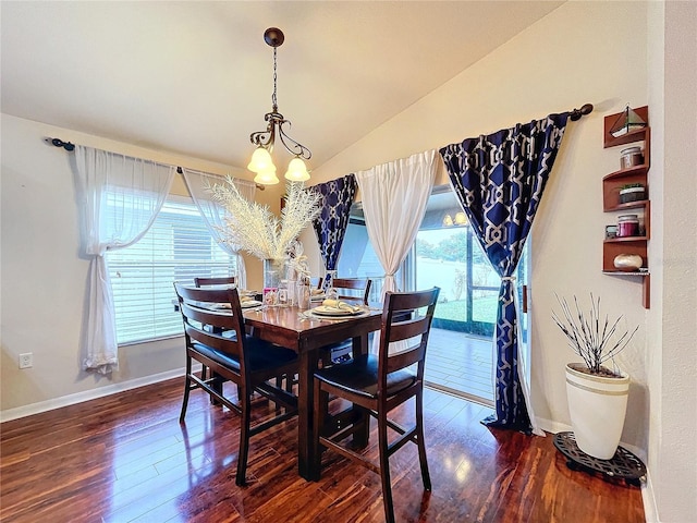 dining area featuring dark wood-type flooring, lofted ceiling, and a notable chandelier