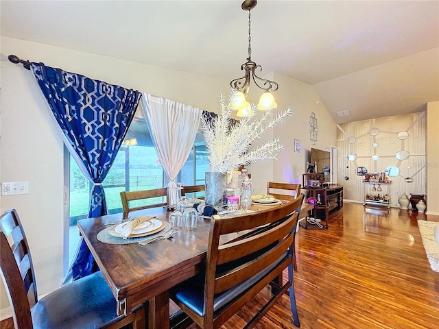 dining room featuring hardwood / wood-style floors, a chandelier, and vaulted ceiling