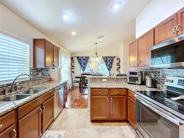 kitchen with sink, decorative light fixtures, lofted ceiling, decorative backsplash, and appliances with stainless steel finishes