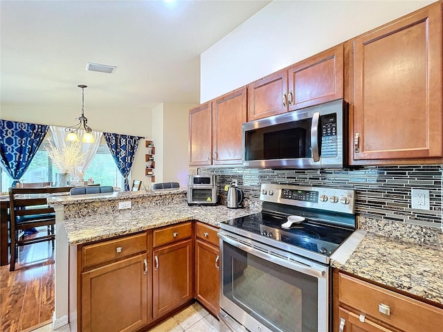 kitchen with pendant lighting, light tile patterned floors, a notable chandelier, kitchen peninsula, and stainless steel appliances