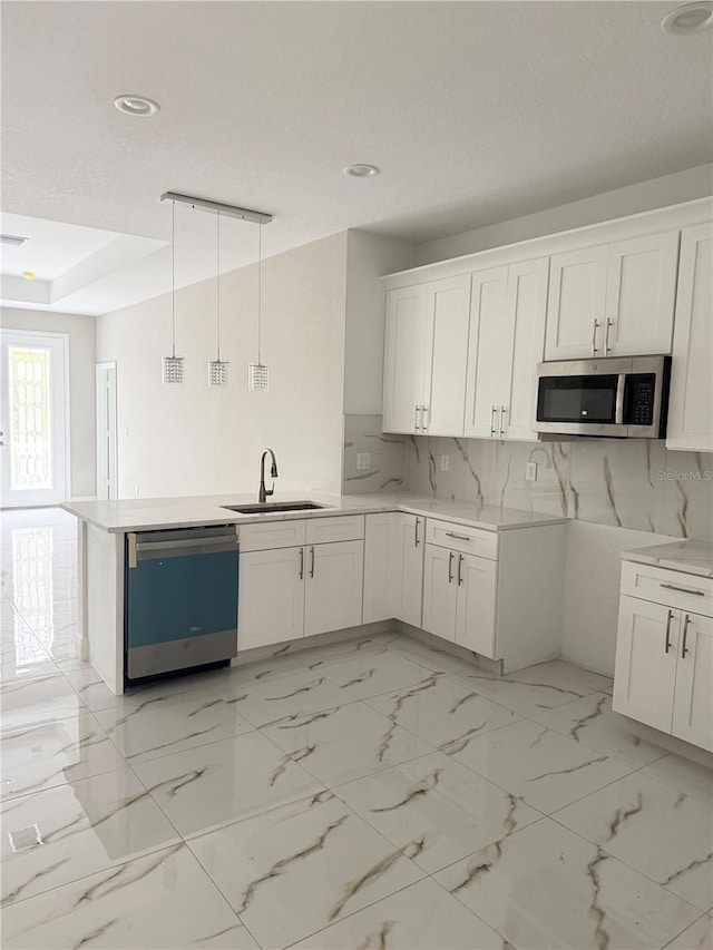 kitchen with appliances with stainless steel finishes, tasteful backsplash, sink, white cabinetry, and hanging light fixtures