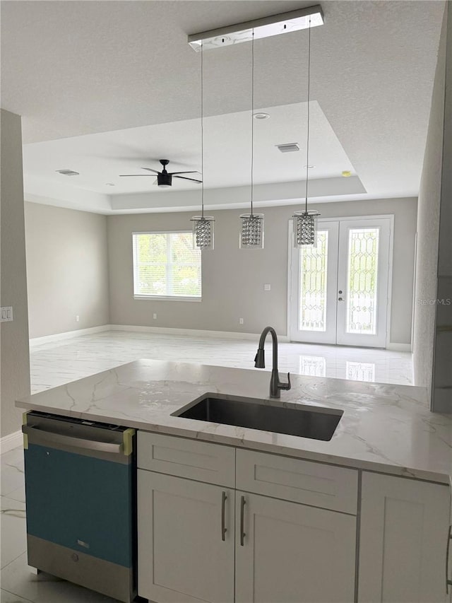 kitchen featuring french doors, sink, stainless steel dishwasher, a tray ceiling, and light stone counters