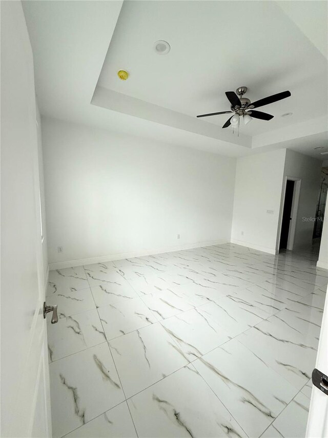 spare room featuring a tray ceiling and ceiling fan