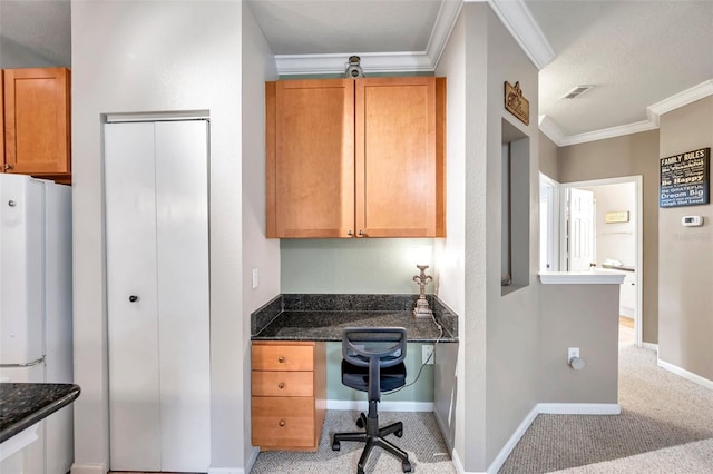 kitchen featuring light carpet, built in desk, dark stone counters, and ornamental molding