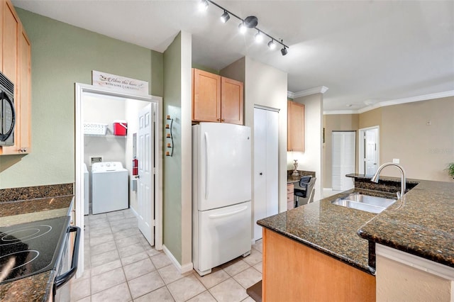 kitchen with dark stone counters, crown molding, sink, white refrigerator, and washer / dryer