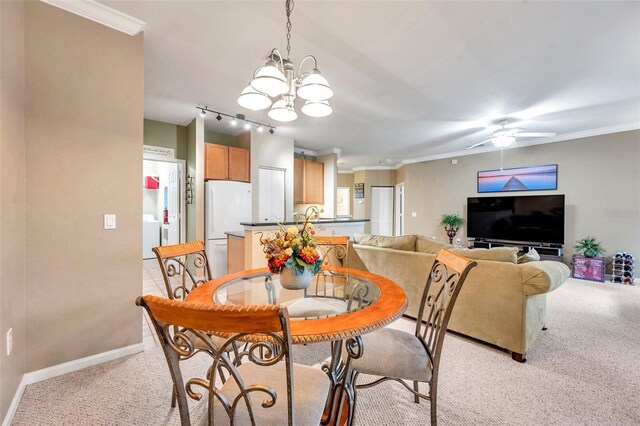 dining space with light carpet, rail lighting, ceiling fan with notable chandelier, and ornamental molding