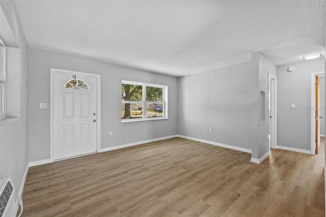 foyer entrance with a textured ceiling and light wood-type flooring